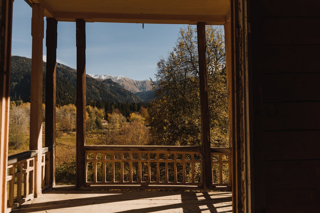 Serene autumn view of mountains from a rustic wooden veranda, capturing nature's beauty.