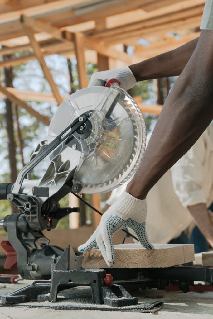 Carpenter using circular saw to cut wood at a construction site outdoors.